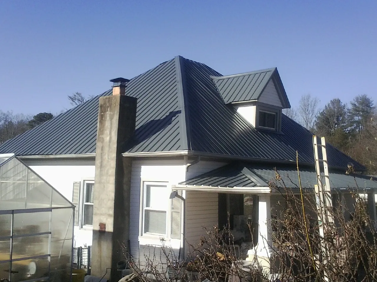 Dark blue standing seam metal roof on a white farmhouse with dormer — Slate & Tile Roof Repair by Roofing Brothers in East Brady