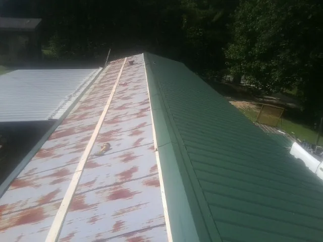 Old rusted panels beside newly installed green metal roofing — Wind Damage Roof Repair by Roofing Brothers in East Brady