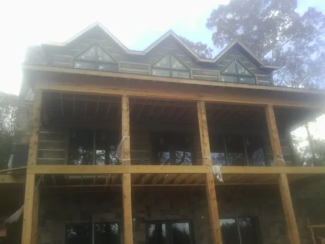 Dormers and porch framing on a large log home under construction — Roof Coating work by our crew in East Brady