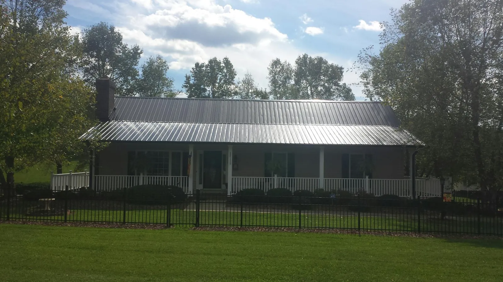 Gray metal roof on a brick ranch with a full width front porch — Gutter Guard Installation work by our crew in East Brady