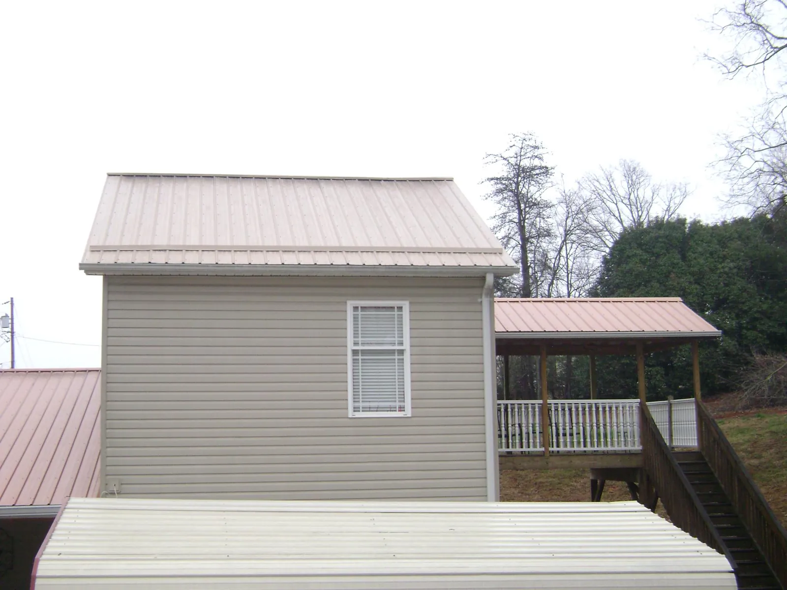 Tan metal roofs on a two story addition and attached porch, from a Roof Replacement job in East Brady