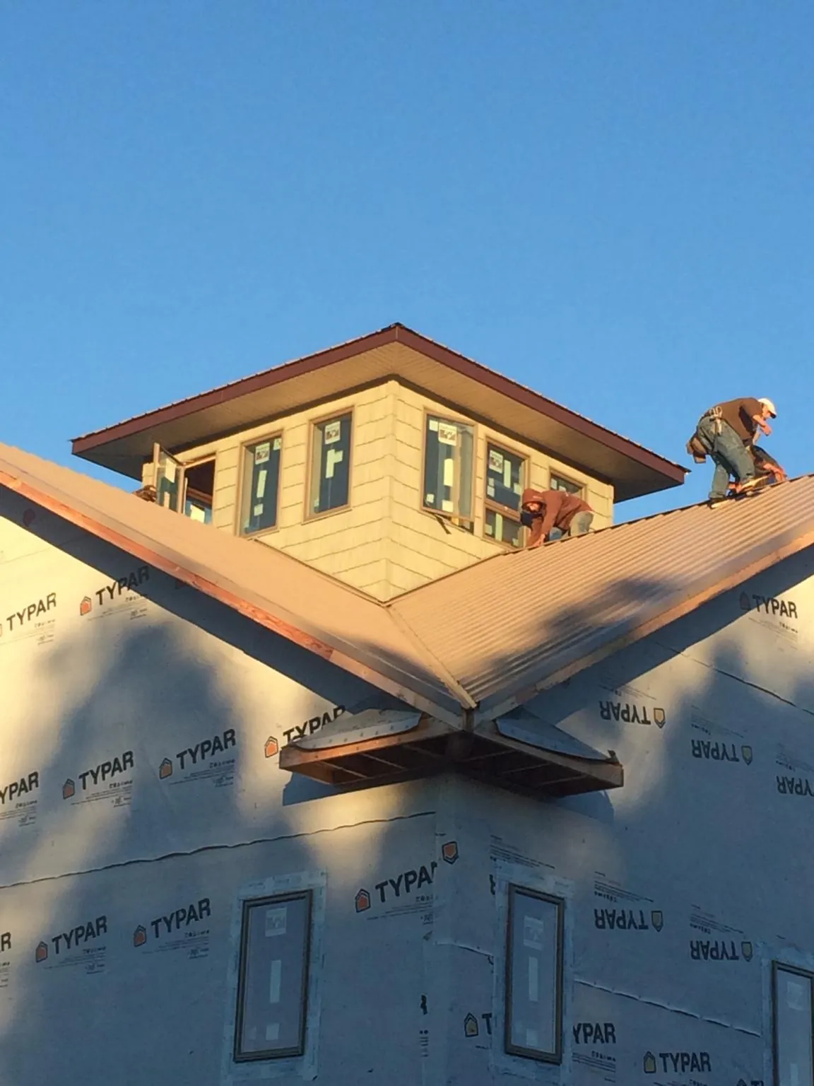 Roofers working around a rooftop cupola on a new metal roof at sunset — Roof Waterproofing in East Brady by Roofing Brothers
